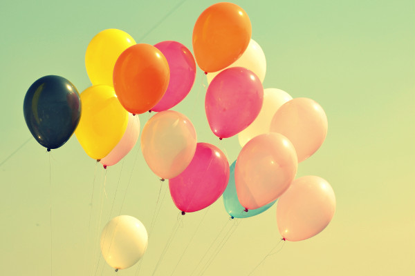 photo de ballons de baudruche colorés sur fond de ciel sous un filtre jaune qui évoque la joie